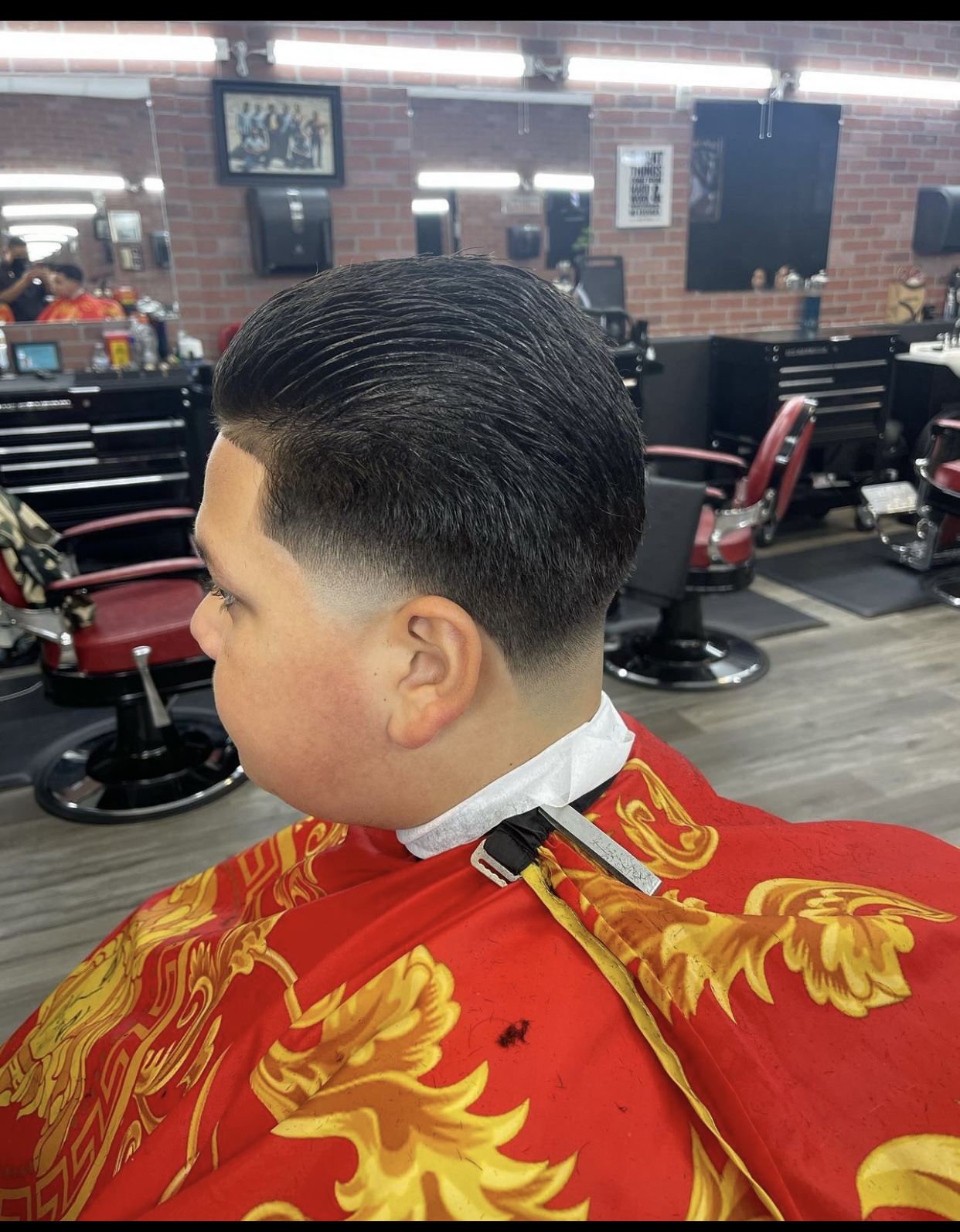 Side profile of a men's slicked-back haircut with a low taper fade